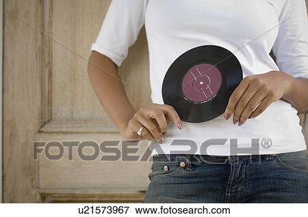 Stock Photo - Mid section view of a woman holding a record in her hands. Fotosearch