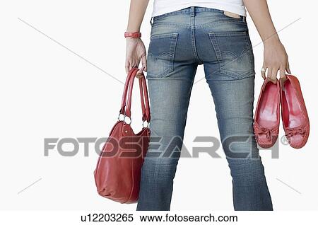 Mid section view of a woman holding a hand bag and a pair of shoes View Large Photo Image Stock Photography - Mid section view of a woman holding a hand bag and a pair of shoes. Fotosearch