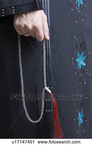 Stock Image - Mid section view of a woman holding prayer beads. Fotosearch