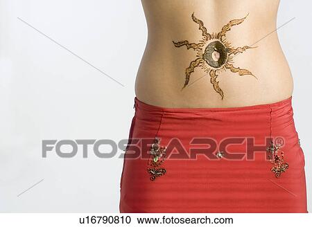 Stock Image - Mid section view of a woman with tattoo on her abdomen. Fotosearch