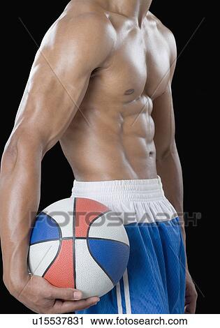 Mid section view of a young man holding a basketball View Large Photo Image Stock Image - Mid section view of a young man holding a basketball. Fotosearch