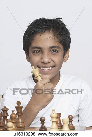 Stock Photo - Portrait of a boy holding a chess piece and smiling. Fotosearch