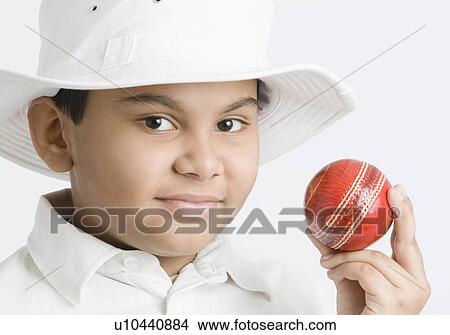 Picture - Portrait of a boy holding a cricket ball. Fotosearch