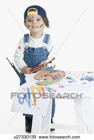 Stock Photo - Portrait of a boy holding a paintbrush and smiling. Fotosearch