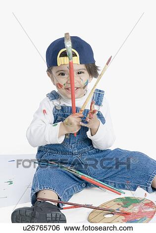Stock Photograph - Portrait of a boy holding a paintbrush and smiling. Fotosearch