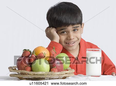 Portrait of a boy making a face in front of a glass of milk and a basket of fruits View Large Photo Image Stock Image - Portrait of a boy making a face in front of a glass of milk and a basket of fruits. Fotosearch