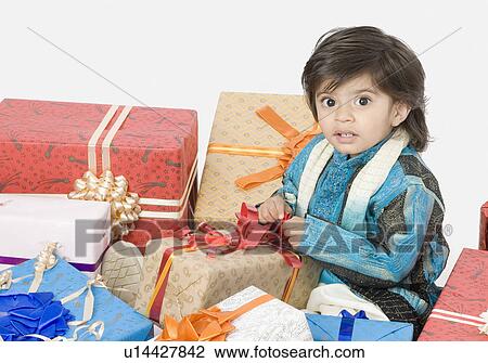 Stock Image - Portrait of a boy opening a present. Fotosearch