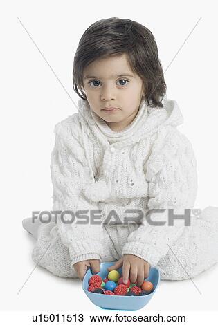 Stock Image - Portrait of a boy playing with candy in a bowl. Fotosearch