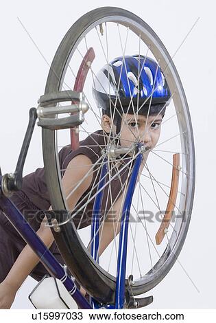 Stock Image - Portrait of a boy posing behind a bicycle. Fotosearch
