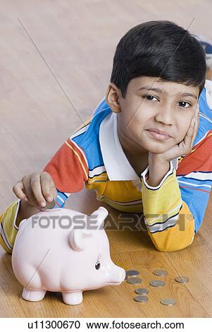 Portrait of a boy putting a coin in a piggy bank View Large Photo Image Stock Image - Portrait of a boy putting a coin in a piggy bank. Fotosearch
