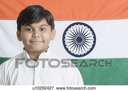 Stock Photo - Portrait of a boy smiling in front of the Indian flag. Fotosearch