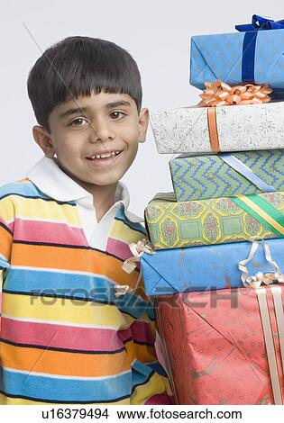 Portrait of a boy standing beside a stack of presents View Large Photo Image Picture - Portrait of a boy standing beside a stack of presents. Fotosearch