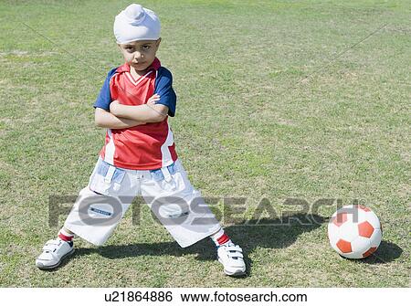 Portrait of a boy standing near a soccer ball with his arms crossed View Large Photo Image Stock Photograph - Portrait of a boy standing near a soccer ball with his arms crossed. Fotosearch