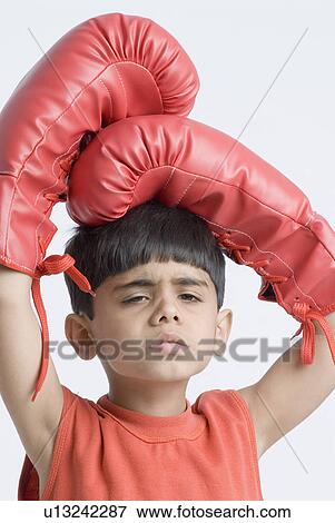 Stock Photo - Portrait of a boy wearing boxing gloves and looking sad. Fotosearch