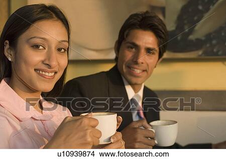 Portrait of a businessman and a businesswoman holding coffee cups and smiling View Large Photo Image Picture - Portrait of a businessman and a businesswoman holding coffee cups and smiling. Fotosearch