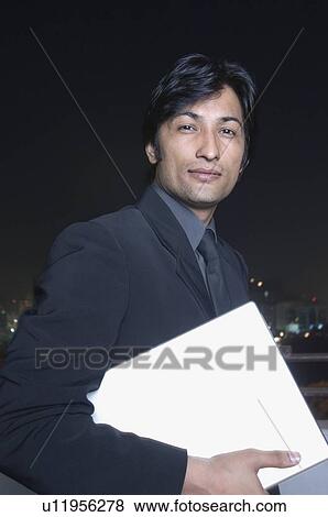 Stock Photo - Portrait of a businessman holding a laptop. Fotosearch