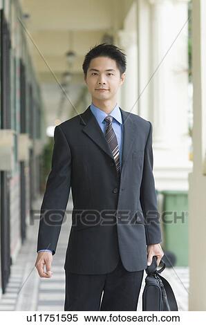 Stock Photography - Portrait of a businessman holding a briefcase and walking. Fotosearch