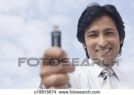 Portrait of a businessman holding a USB pen drive View Large Photo Image Picture - Portrait of a businessman holding a USB pen drive. Fotosearch
