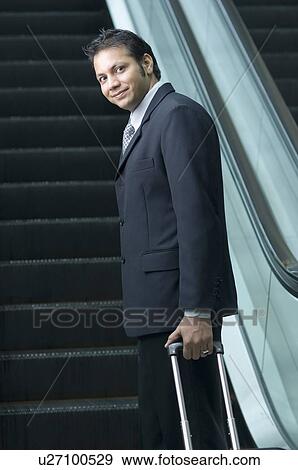 Stock Photo - Portrait of a businessman standing in front of an escalator. Fotosearch