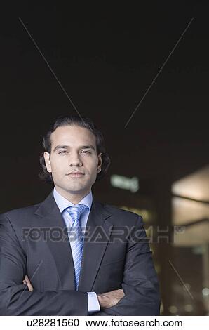 Stock Image - Portrait of a businessman standing with his arms crossed. Fotosearch
