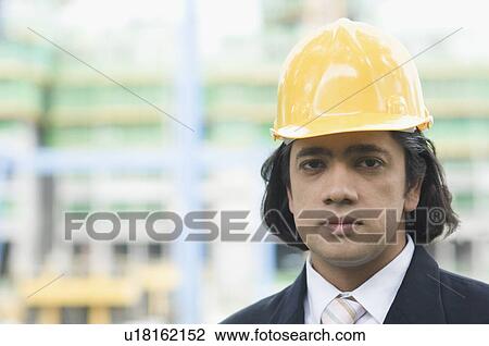 Stock Image - Portrait of a businessman wearing a hardhat. Fotosearch
