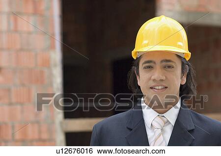 Stock Photograph - Portrait of a businessman wearing a hardhat. Fotosearch