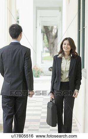 Portrait of a businesswoman and a businessman walking in the corridor View Large Photo Image Stock Photograph - Portrait of a businesswoman and a businessman walking in the corridor. Fotosearch