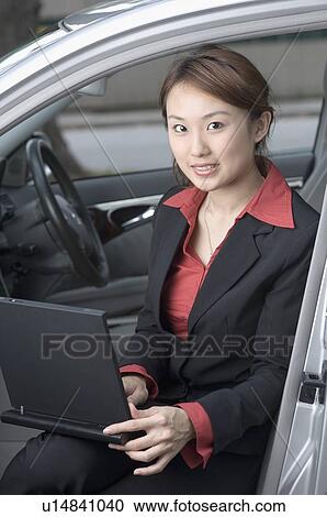 Portrait of a businesswoman sitting in a car and using a laptop View Large Photo Image Stock Image - Portrait of a businesswoman sitting in a car and using a laptop. Fotosearch