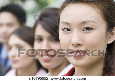 Stock Image - Portrait of a businesswoman smiling with her colleagues behind her. Fotosearch