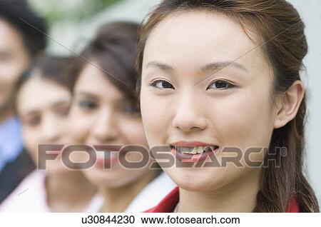 Portrait of a businesswoman smiling with her colleagues behind her View Large Photo Image Stock Image - Portrait of a businesswoman smiling with her colleagues behind her. Fotosearch