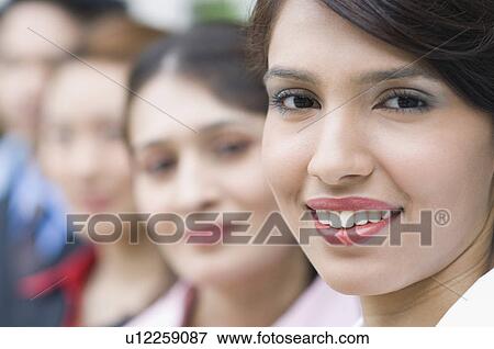Portrait of a businesswoman smiling with her colleagues behind her View Large Photo Image Stock Photo - Portrait of a businesswoman smiling with her colleagues behind her. Fotosearch