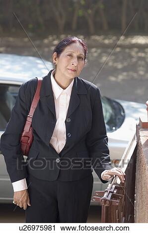 Portrait of a businesswoman standing at a gate View Large Photo Image Stock Image - Portrait of a businesswoman standing at a gate. Fotosearch