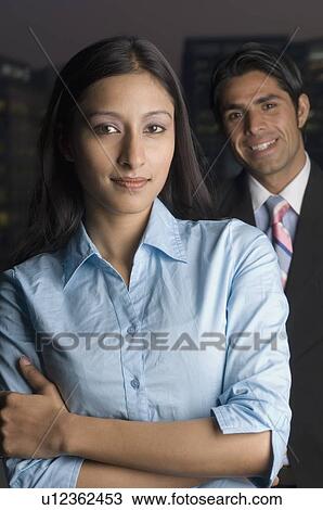 Stock Image - Portrait of a businesswoman standing with a businessman behind her. Fotosearch