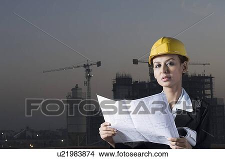 Picture - Portrait of a businesswoman wearing a hardhat and holding a blueprint. Fotosearch
