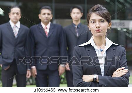 Stock Image - Portrait of a businesswoman with three businessmen standing behind her. Fotosearch