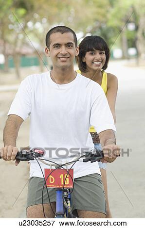 Portrait of a couple sitting on a bicycle View Large Photo Image Stock Photo - Portrait of a couple sitting on a bicycle. Fotosearch