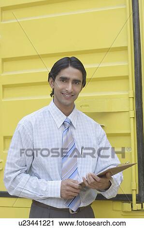 Portrait of a delivery man holding a clipboard and smiling View Large Photo Image Stock Image - Portrait of a delivery man holding a clipboard and smiling. Fotosearch