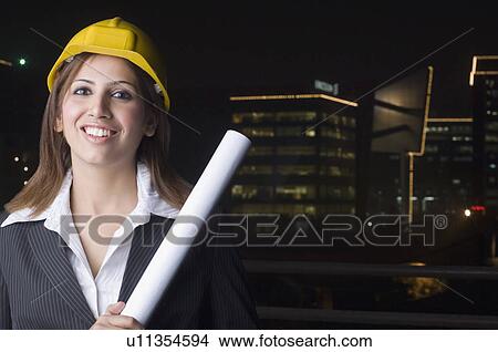 Portrait of a female architect holding a blueprint and smiling View Large Photo Image Picture - Portrait of a female architect holding a blueprint and smiling. Fotosearch