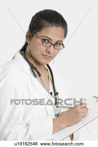 Stock Photograph - Portrait of a female doctor writing on a clipboard. Fotosearch