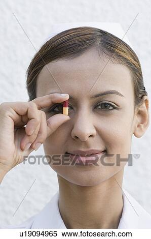 Portrait of a female nurse holding a capsule View Large Photo Image Stock Photography - Portrait of a female nurse holding a capsule. Fotosearch