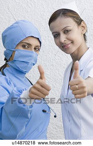 Portrait of a female surgeon and a female nurse making a thumbs up signs View Large Photo Image Stock Photo - Portrait of a female surgeon and a female nurse making a thumbs up signs. Fotosearch