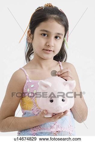 Portrait of a girl dropping a coin into a piggy bank View Large Photo Image Stock Photo - Portrait of a girl dropping a coin into a piggy bank. Fotosearch