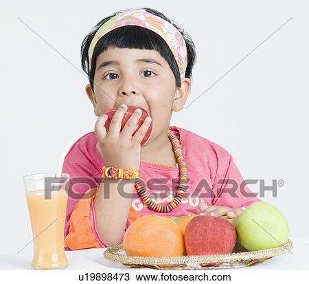 Stock Image - Portrait of a girl eating an apple. Fotosearch