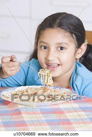 Stock Photo - Portrait of a girl eating spaghetti with a fork. Fotosearch