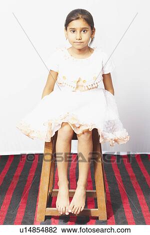 Stock Image - Portrait of a girl sitting on a stool. Fotosearch