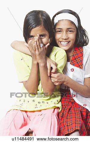 Stock Image - Portrait of a girl sitting with her arm around another girl. Fotosearch