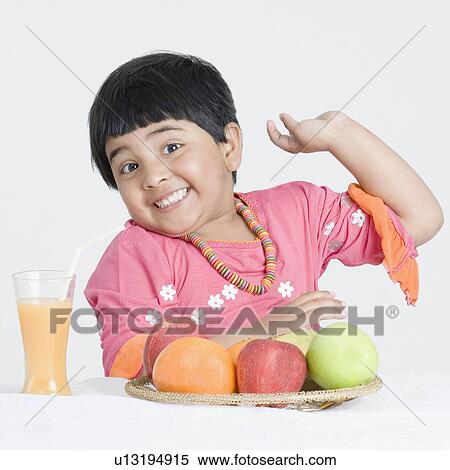 Portrait of a girl smiling at a tray of fruits in front of her View Large Photo Image Stock Photography - Portrait of a girl smiling at a tray of fruits in front of her. Fotosearch