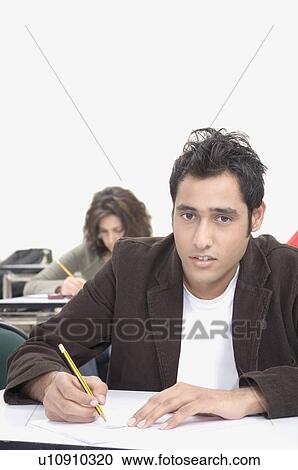 Stock Image - Portrait of a male college student giving an exam in a classroom. Fotosearch
