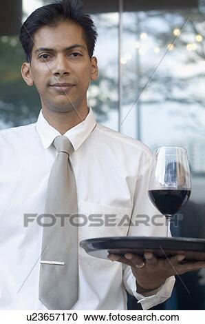 Portrait of a mid adult man holding a glass of red wine on a tray View Large Photo Image Stock Image - Portrait of a mid adult man holding a glass of red wine on a tray. Fotosearch