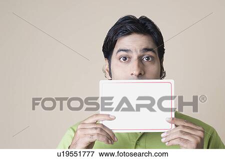 Portrait of a mid adult man holding a blank placard over his mouth View Large Photo Image Stock Photo - Portrait of a mid adult man holding a blank placard over his mouth. Fotosearch